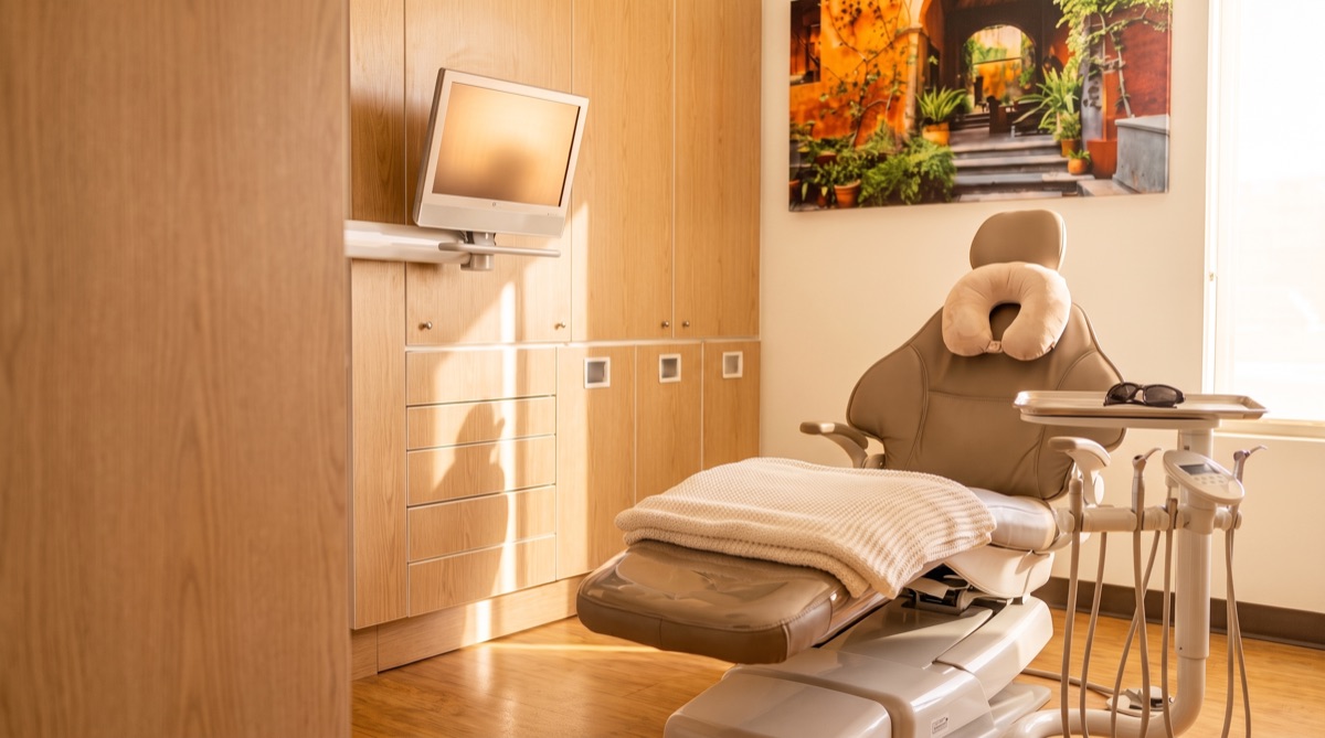 A treatment room set up with a blanket, neck pillow, and sunglasses ready for a patient